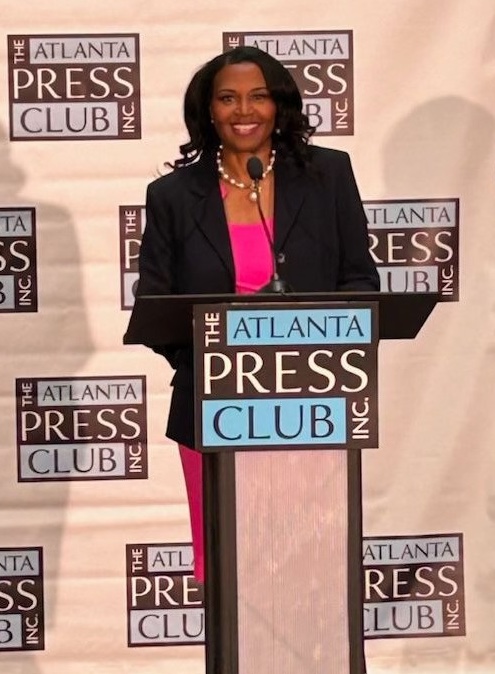 Karen Renéstanding at podium — at Georgia Public Broadcasting